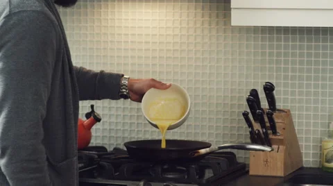 Man preparing a scrambled eggs in kitchen Stock Footage 63860646