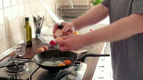 Man preparing scrambled eggs in the kitchen at home, focus on hands Stock Footage 102914396