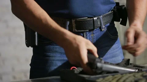 A man preparing to shoot a gun. puts the gun in the holster Stock Footage 63846143