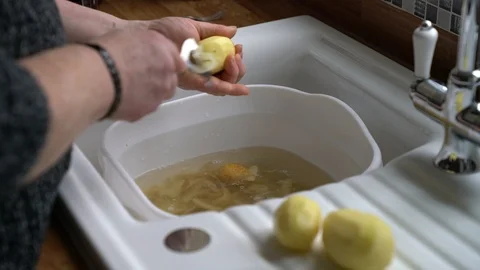 Man preparing small potatoes over kitchen sink using peeler 스톡 동영상 86980546
