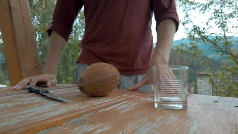 Man preparing to split ripe coconut into two halves and pour coconut water into  Stock Photos