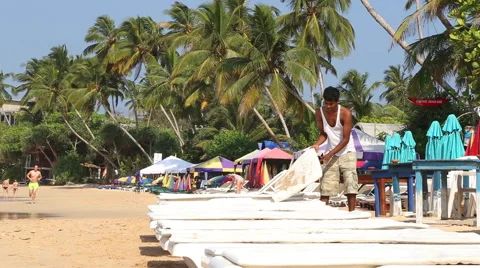 Man preparing sun beds for tourists on beach in Mirissa, Sri Lanka. Stock Footage 40337860