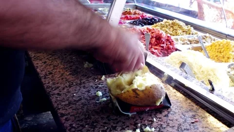 A man preparing tarditional Turkish food called kumpir made by baked potatoes Stock Footage 105190646