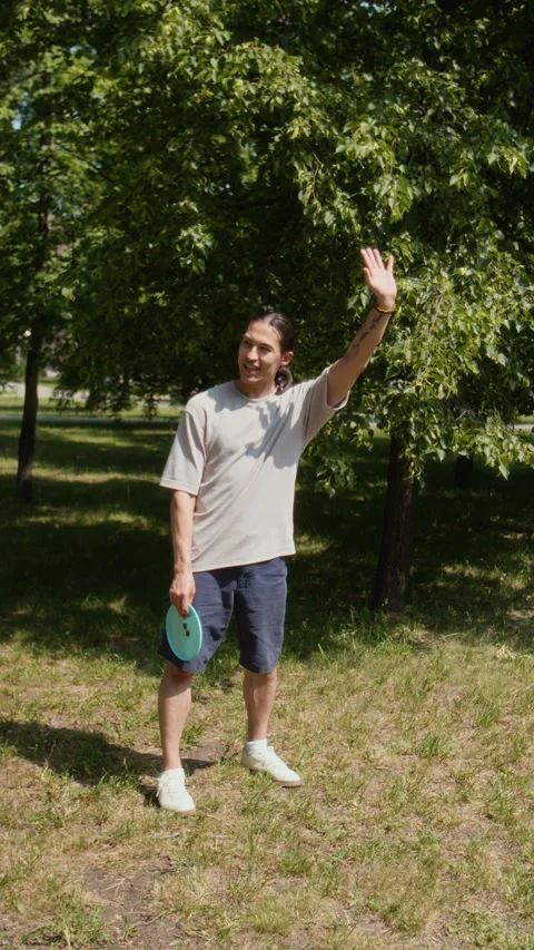 Man Preparing to Throw Frisbee on Sunny, Grassy Park Lawn Stock Footage 314038993