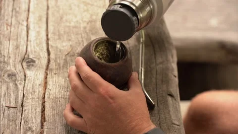 Man preparing traditional yerba mate infusion on rustic wooden surface Stock Footage 312822264