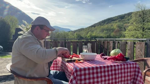 Man Preparing Vegetables at Rustic Outdoor Table with Scenic View Stock Footage 333523488