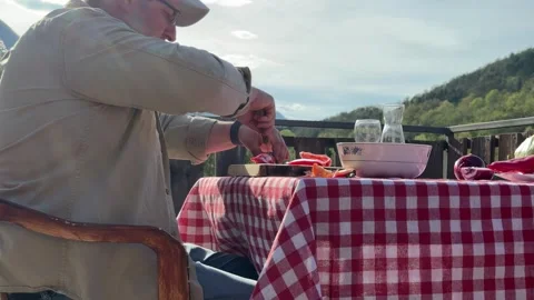 Man Preparing Vegetables at Rustic Outdoor Table with Scenic View 動画素材 333523505
