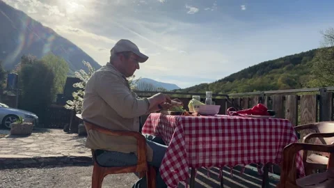 Man Preparing Vegetables at Rustic Outdoor Table with Scenic View Stock Footage 333523539