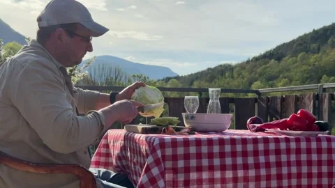 Man Preparing Vegetables at Rustic Outdoor Table with Scenic View Stock Footage 333523547