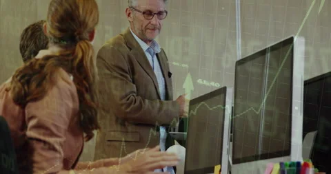Man presenting finance data on monitors causing chart overlays, colleagues Stock Footage 314174876