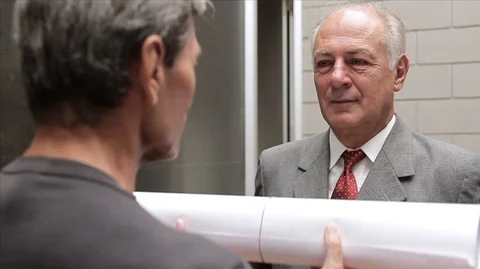 Man presenting rolled documents/building plans to a businessman and then shaking Vídeos de archivo 88407103