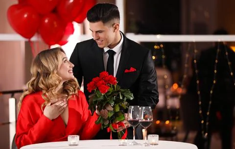 Man presenting roses to his beloved woman in restaurant at Valentine's day di Stock Photos