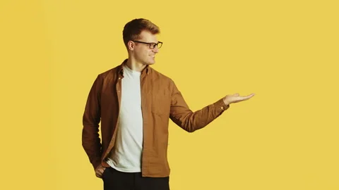 Man presenting something on yellow background Stock Footage 288224593