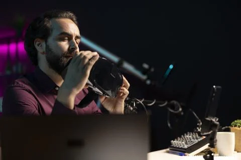 Man presenting VR goggles to audience, filming video with smartphone on tripod Stock Photos