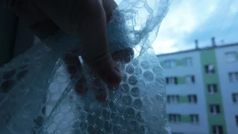 Man Presses Bubble Wrap by Window Concept of Mental Shield Against Chaos Outside Stock Footage 319059698