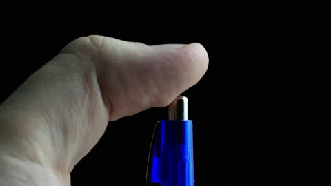 A man presses the button of a ballpoint pen on a black background. Nervous Stockbeeldmateriaal 152484651