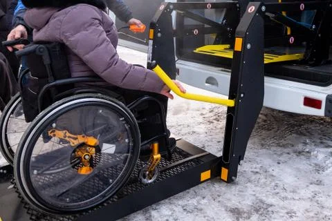 A man presses a button on the control panel to pick up a woman in a wheelchai Photos