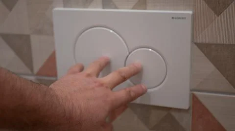 Man presses a button on the drain tank in the bathroom Photos