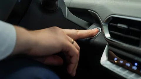 A man presses the car engine start button. Stock Photos