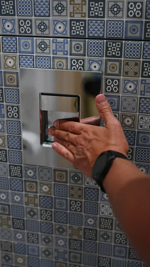 Man presses flush panel on mosaic wall in bathroom. Man presses flush panel with Stock Footage 331061420