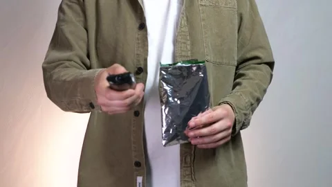 A man presses the TV remote control while holding a bag of snacks, chips or Stock Footage 312797044