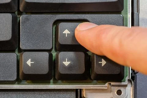 Man pressing the up arrow key on a simple laptop computer keyboard, top dow.. Stock Photos