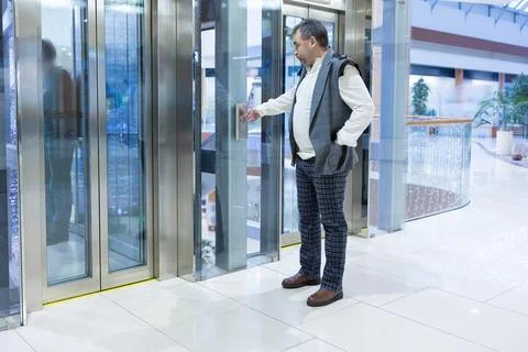 Man Pressing Elevator Button in Modern Building Stock Photos