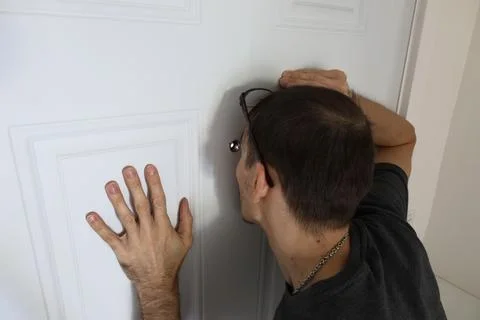 Man pressing hand on door while looking through peephole security concept 写真素材