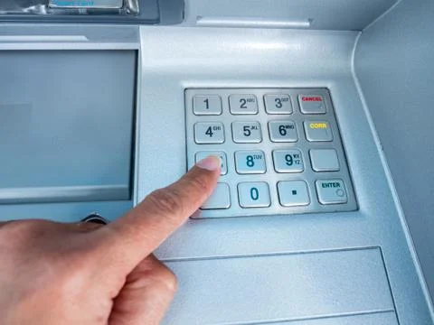 The man is pressing the secret code on the ATM's numeric keypad with the inde Foto stock