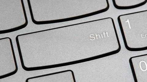 Man pressing the shift key on a modern laptop computer keyboard closeup top.. Stock Photos