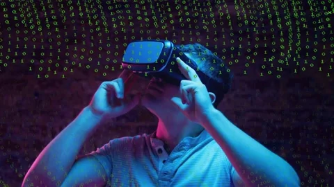Man pressing VR headset sides activating green binary overlay exploring VR by Stock Footage 333837171