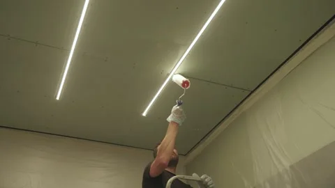 A man primes a drywall ceiling with a roller Stock Footage 323116436