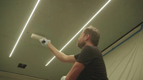 A man primes a drywall ceiling with a roller Stock Footage 323116772