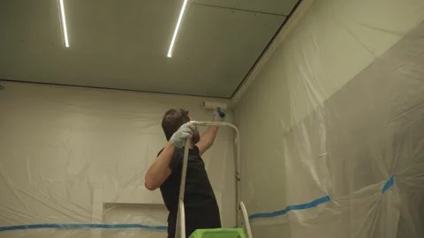 A man primes a drywall ceiling with a roller Stock Footage 323116865