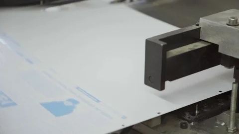 Man in printing bends corners on sheet of paper on machine Stock Footage 71312076