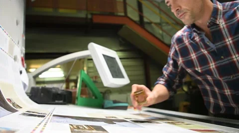 Man in printing house controling sample before edition Stock Footage 59771324