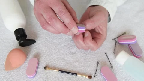 A man processes the tips of his nails on his hand with a small nail file. Stock Footage 151579383
