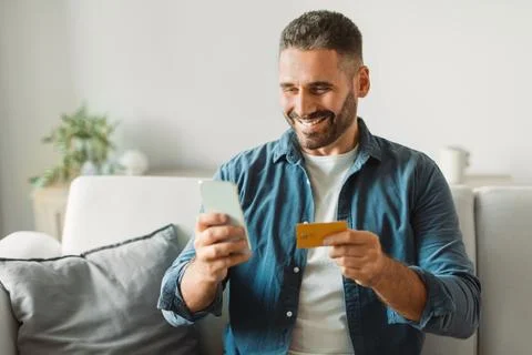 Man processing payment through smartphone and credit card indoor 스톡 사진