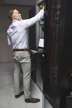 Man, programmer and cables with laptop in server room for programming, coding Stock-Fotos