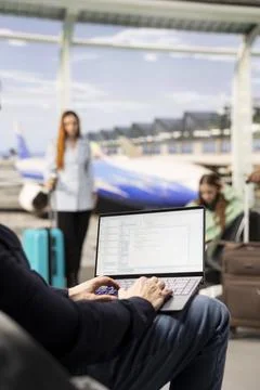 Man programmer, coding on laptop, digital nomad in airport, writing binary code Stockfoto's