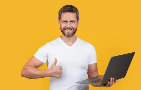 Man programmer with laptop show thumb up isolated on yellow background. man 스톡 사진