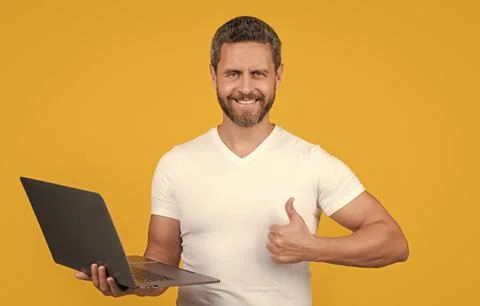 Man programmer with laptop show thumb up isolated on yellow background. man 스톡 사진