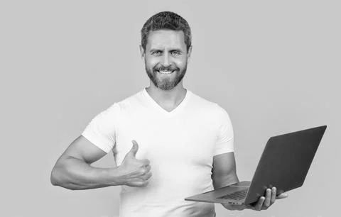 Man programmer with laptop show thumb up isolated on yellow background. man 스톡 사진