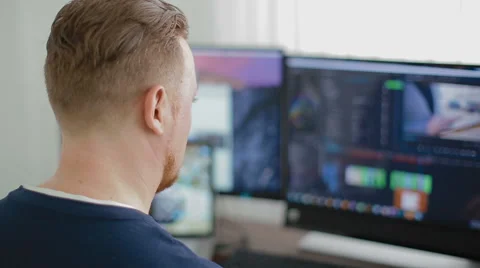 The man the programmer works at the computer and three monitors Stock Footage 62519081