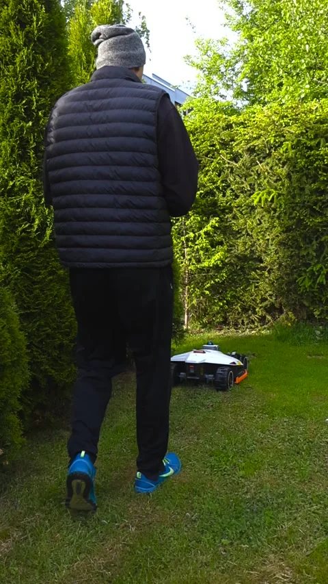 Man Programming a Robotic Lawn Mower with a Smartphone App in a Garden 動画素材 336652470