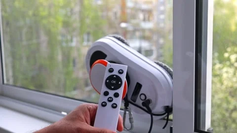 A man programs a window cleaning robot using a remote control. Stock Footage 276314999