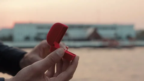 Man proposals with elegant engagement ring in box on yacht against calm harbor Stock Footage 308407183