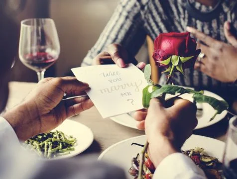 Man proposing with a red rose at the dinner table Stock Photos
