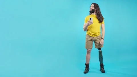 Man with prosthetic leg with the mobile looking aside 動画素材 228801622