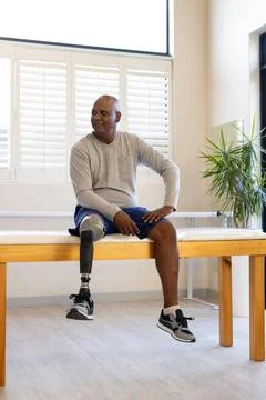 Man with prosthetic leg sitting on table, smiling and looking away Stock Photos